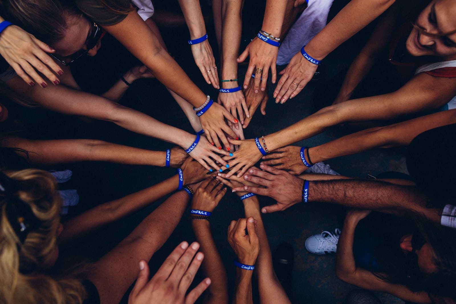 Many hands from different people meeting in the centre of a circle.