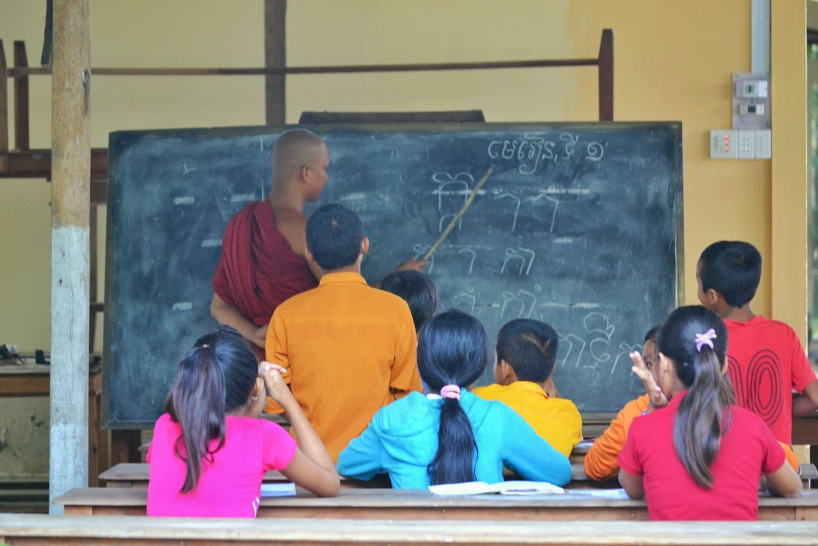 A teacher at a chalkboard leading a lesson for a small group of children.