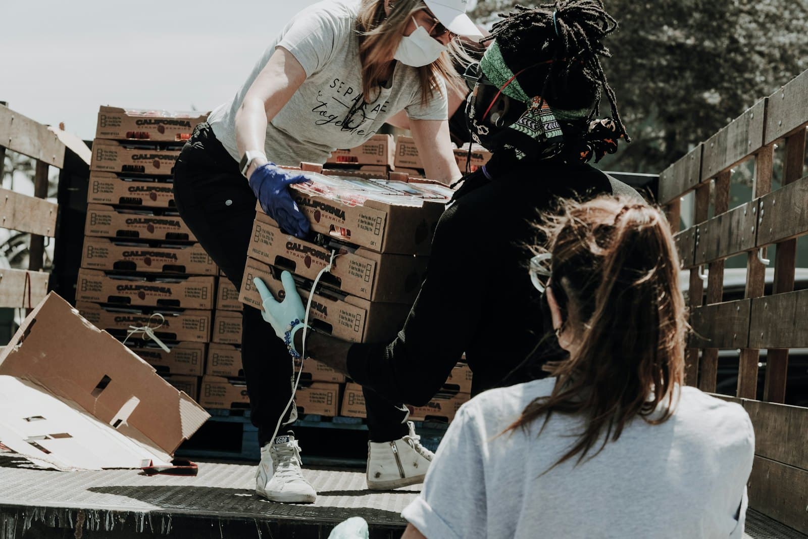 Volunteers in face masks loading boxes of fresh produce onto a truck.